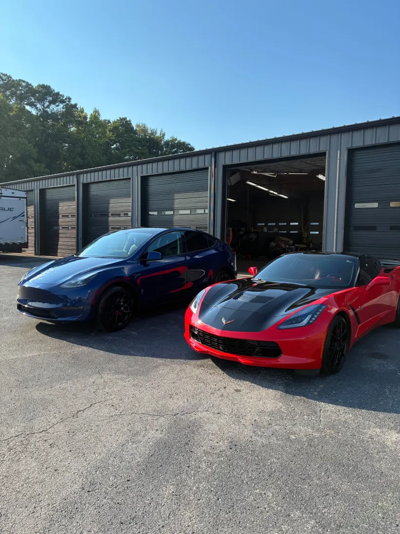 Tesla Model Y and Corvette Stingray outside the bays